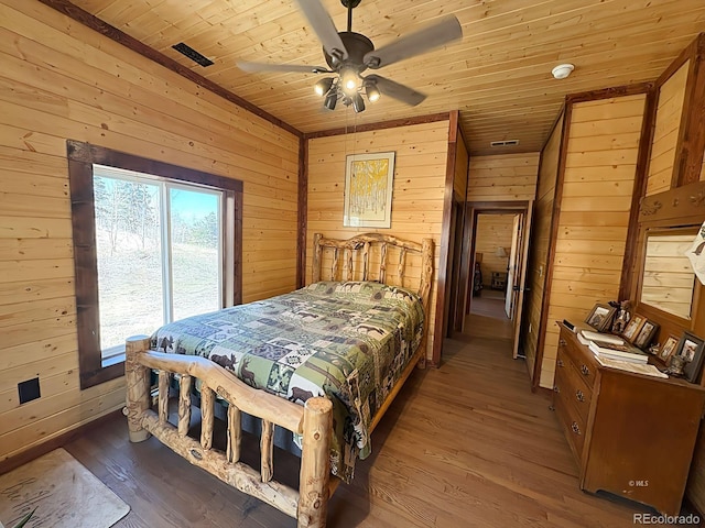 bedroom featuring wooden ceiling, ceiling fan, visible vents, wood walls, and wood finished floors