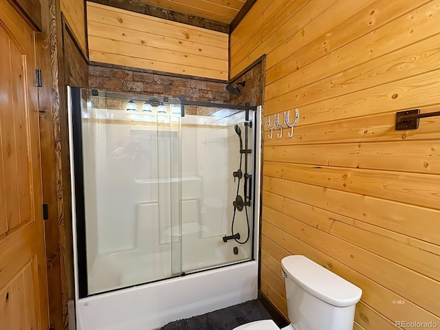 full bath featuring toilet, wood walls, and shower / bath combination with glass door