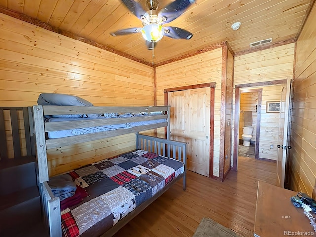 bedroom featuring wooden ceiling, wood walls, wood finished floors, and visible vents
