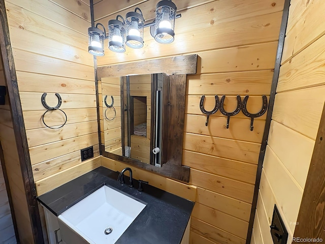 bathroom featuring wooden walls and a sink