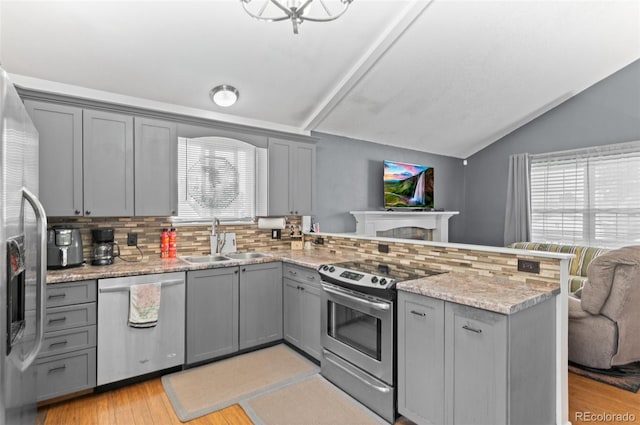 9648 Lane St, Thornton, CO 80260 - kitchen featuring stainless steel appliances, gray cabinets, a peninsula, decorative backsplash, and lofted ceiling