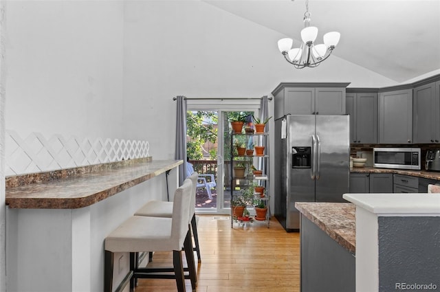 9648 Lane St, Thornton, CO 80260 - kitchen with stainless steel appliances, backsplash, a chandelier, light wood finished floors, and a kitchen breakfast bar