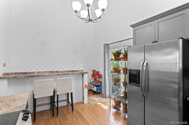 9648 Lane St, Thornton, CO 80260 - kitchen with stainless steel fridge with ice dispenser, light wood finished floors, a chandelier, stove, and gray cabinets