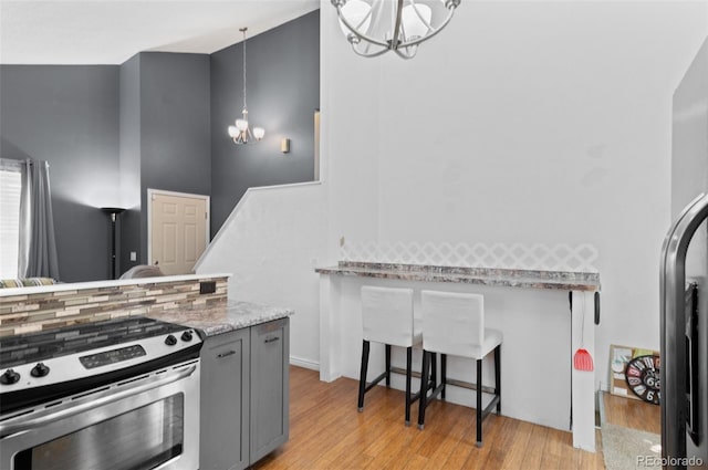 9648 Lane St, Thornton, CO 80260 - kitchen with stainless steel electric stove, a chandelier, light wood finished floors, and gray cabinetry