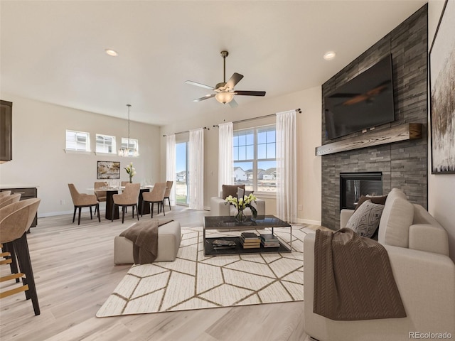 living room featuring ceiling fan, a fireplace, and light wood-type flooring