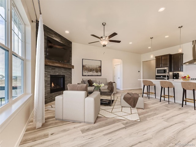 living room with ceiling fan, a fireplace, and light hardwood / wood-style flooring