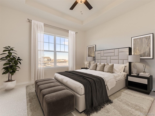 bedroom with a tray ceiling, ceiling fan, and light colored carpet