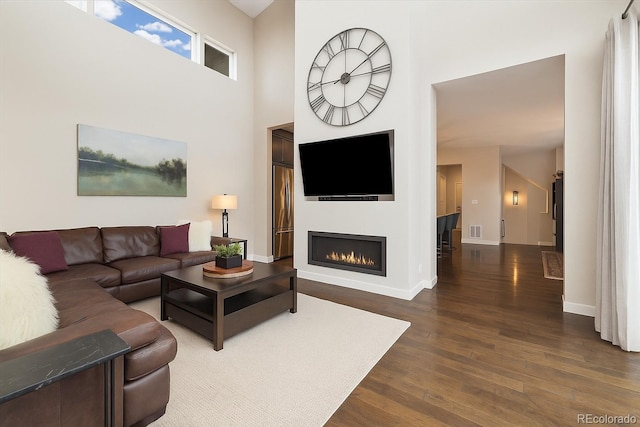 1882 W 67th Ave, Denver, CO 80221 - living area with dark wood-style flooring, a lit fireplace, and a towering ceiling