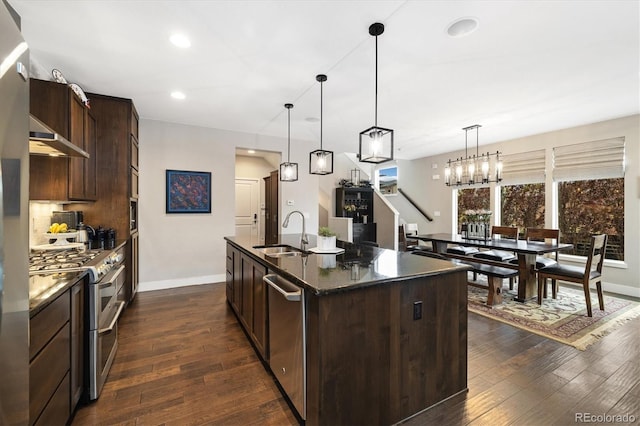 1882 W 67th Ave, Denver, CO 80221 - kitchen with stainless steel appliances, dark brown cabinets, dark wood finished floors, an island with sink, and hanging light fixtures