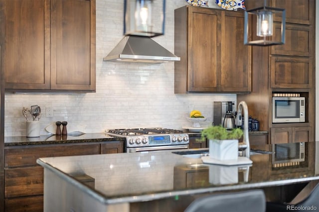 1882 W 67th Ave, Denver, CO 80221 - kitchen featuring gas range, wall chimney range hood, backsplash, dark stone countertops, and pendant lighting