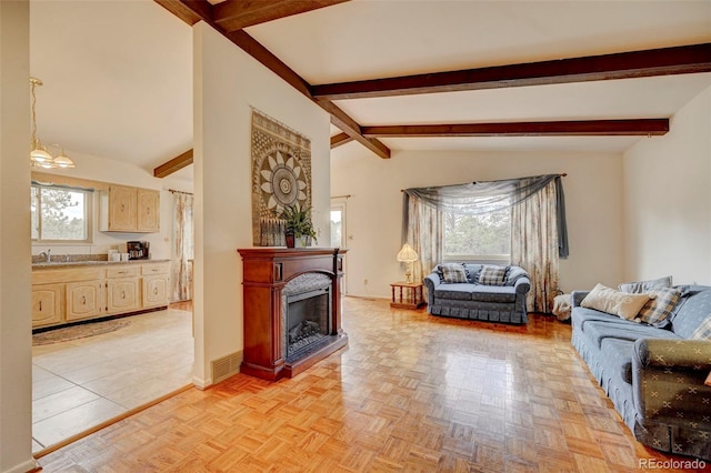 living room featuring light parquet flooring, an inviting chandelier, lofted ceiling with beams, and sink