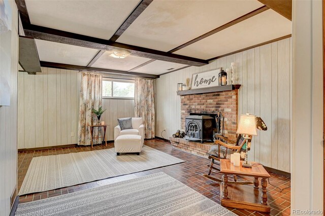 living room with a wood stove, beam ceiling, and wooden walls