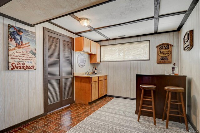 kitchen with a kitchen bar, wooden walls, kitchen peninsula, and sink