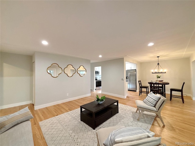 living room with an inviting chandelier and light hardwood / wood-style flooring