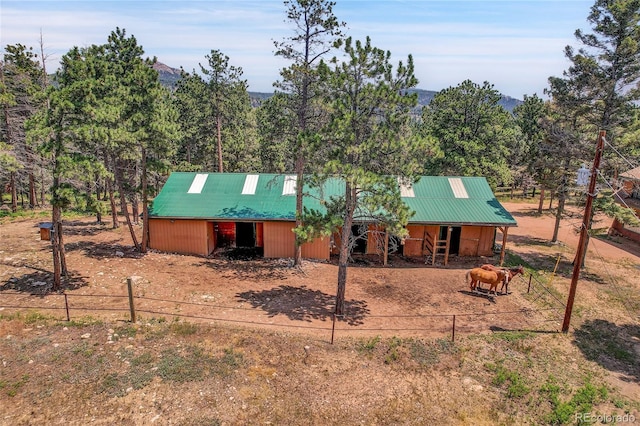 view of front of property with metal roof, fence, an exterior structure, a mountain view, and an outdoor structure