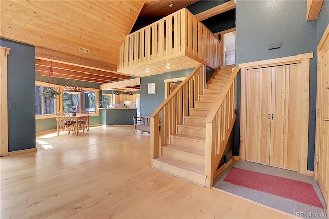 staircase featuring high vaulted ceiling, wooden ceiling, visible vents, and wood finished floors