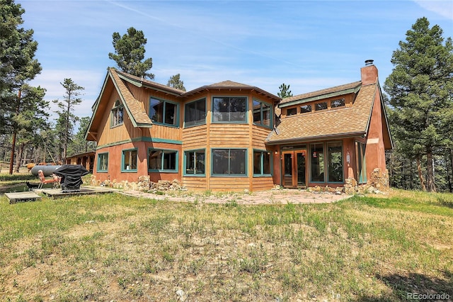 rear view of house with a yard, a shingled roof, a chimney, and a sunroom