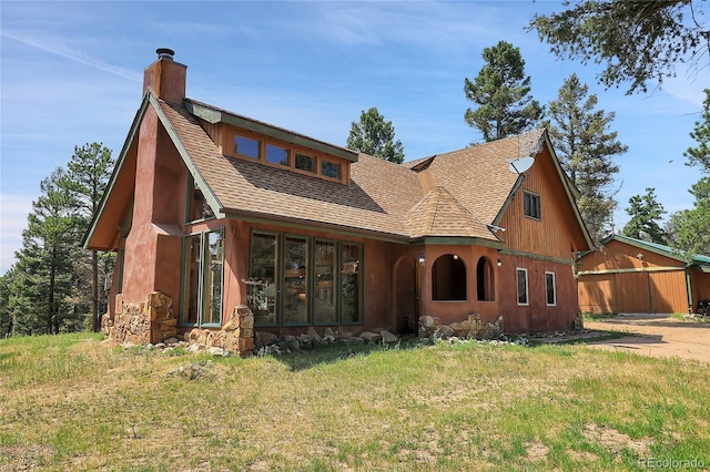 view of front of property featuring roof with shingles, a chimney, and a front lawn