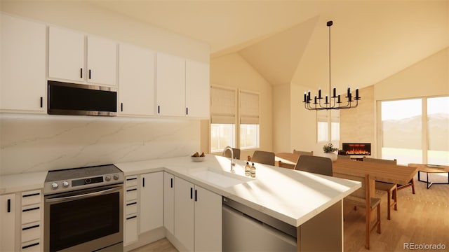 kitchen featuring stainless steel appliances, a peninsula, a sink, a high end fireplace, and vaulted ceiling