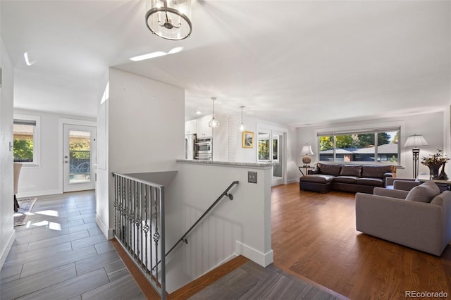 stairway with wood finished floors, baseboards, and a chandelier