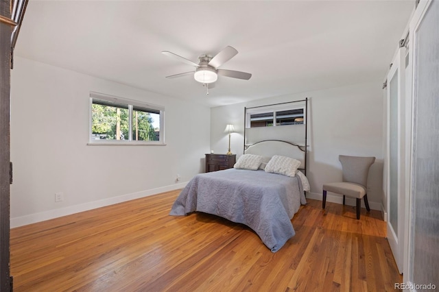 bedroom featuring light wood-type flooring, baseboards, and a ceiling fan