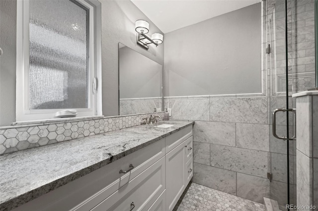 full bath with a wainscoted wall, tile walls, a stall shower, and vanity