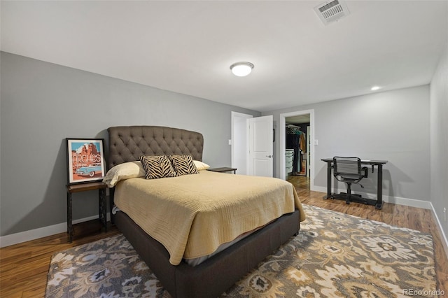 bedroom with visible vents, wood finished floors, a closet, baseboards, and a spacious closet