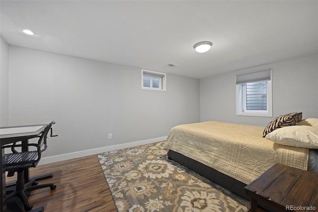 bedroom with visible vents, multiple windows, baseboards, and wood finished floors