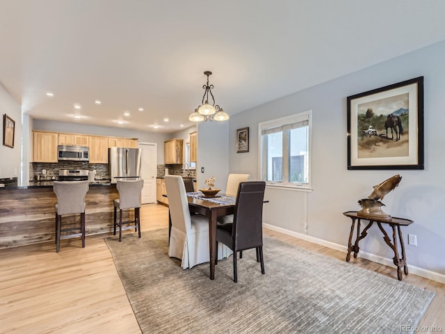 dining area with light hardwood / wood-style flooring and a chandelier