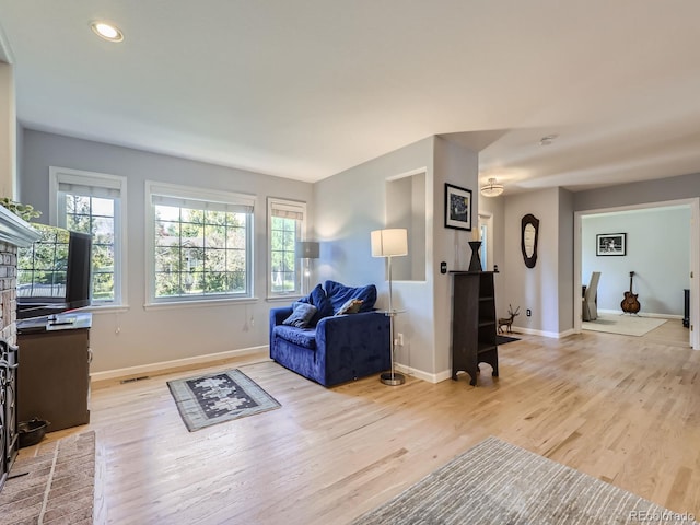 living room featuring light hardwood / wood-style floors and a brick fireplace