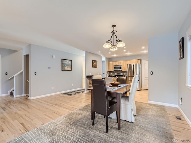 dining space featuring light wood-type flooring and an inviting chandelier