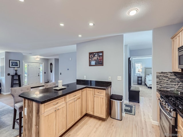 kitchen featuring a kitchen bar, a wealth of natural light, kitchen peninsula, and appliances with stainless steel finishes