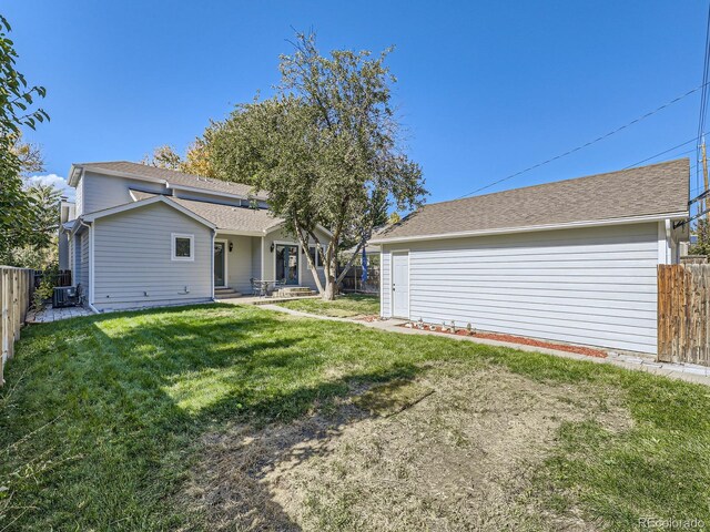 back of property with a yard and central air condition unit