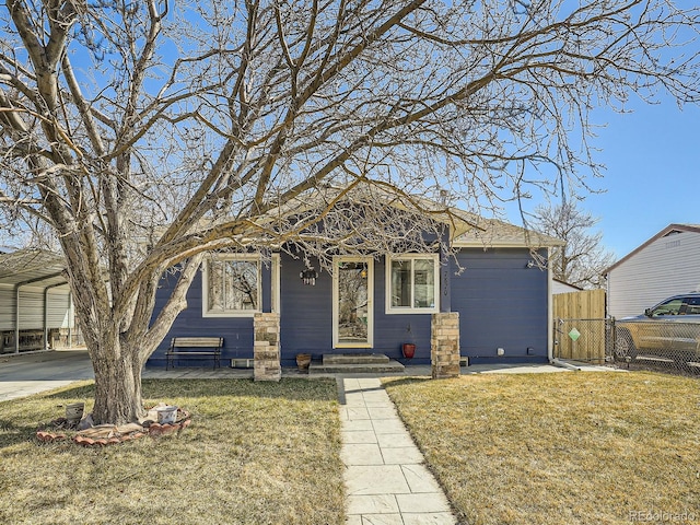 view of front facade featuring driveway, a detached carport, fence, and a front yard