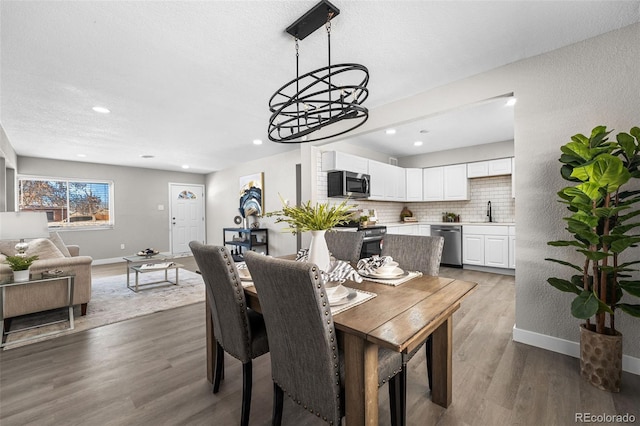 dining area with recessed lighting, a textured ceiling, baseboards, and wood finished floors