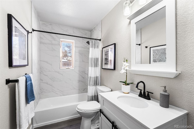 bathroom featuring a textured wall, toilet, wood finished floors, vanity, and shower / bath combo