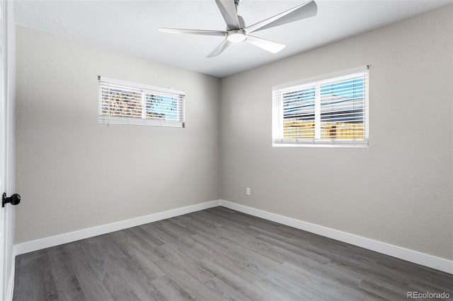 empty room with a ceiling fan, dark wood-style flooring, and baseboards