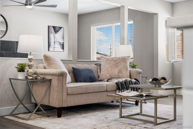 living area featuring a ceiling fan, a textured wall, and wood finished floors