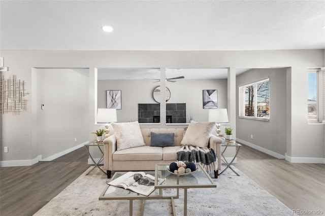 living room featuring a textured ceiling, baseboards, and wood finished floors