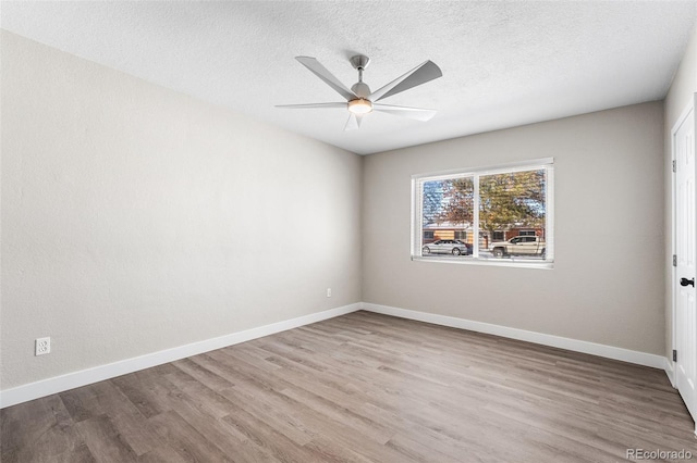 empty room with a ceiling fan, a textured ceiling, baseboards, and wood finished floors