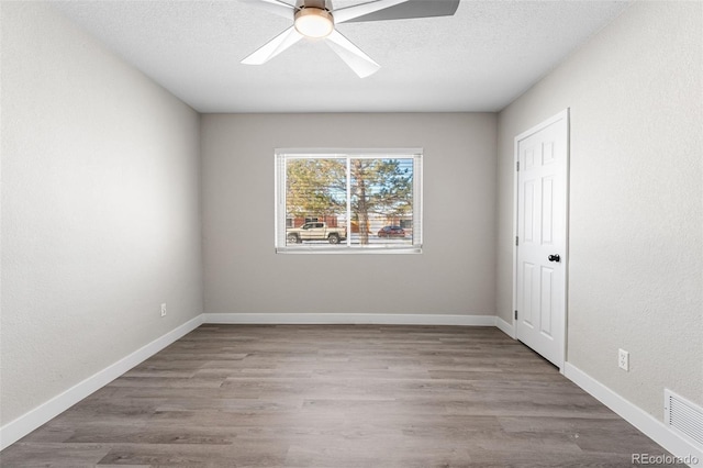 spare room with ceiling fan, a textured ceiling, baseboards, and wood finished floors