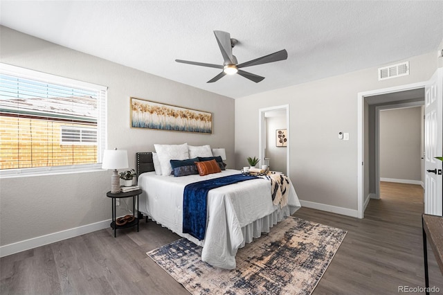 bedroom featuring a textured ceiling, ceiling fan, wood finished floors, visible vents, and baseboards