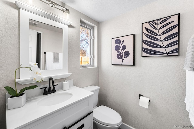 half bath featuring a textured ceiling, a textured wall, toilet, visible vents, and vanity