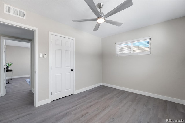 unfurnished room with baseboards, visible vents, ceiling fan, and wood finished floors