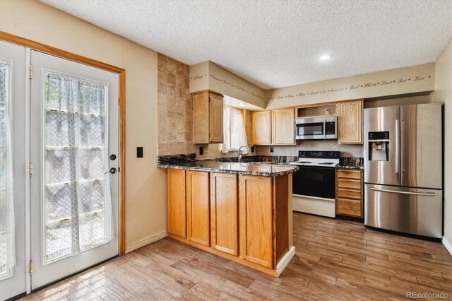 3616 W Radcliff Ave, Denver, CO 80236 - kitchen featuring appliances with stainless steel finishes, a textured ceiling, a peninsula, a sink, and light wood-type flooring