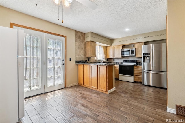 3616 W Radcliff Ave, Denver, CO 80236 - kitchen featuring stainless steel appliances, a textured ceiling, wood finished floors, ceiling fan, and a peninsula