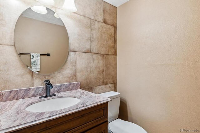 3616 W Radcliff Ave, Denver, CO 80236 - half bathroom featuring vanity, toilet, and a textured wall