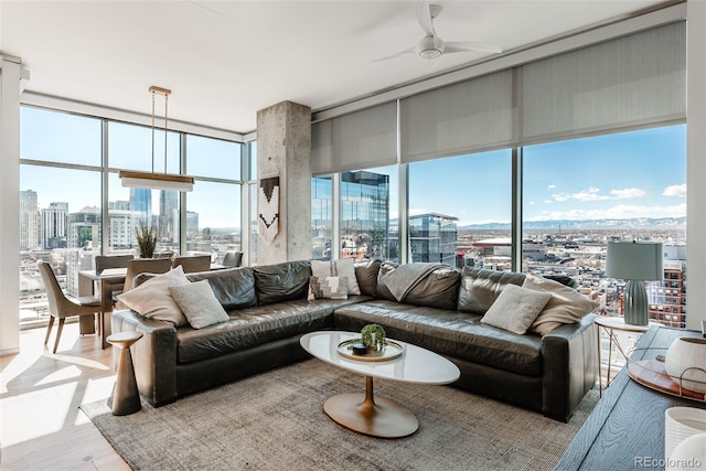 living area with a ceiling fan, a view of city, floor to ceiling windows, and wood finished floors