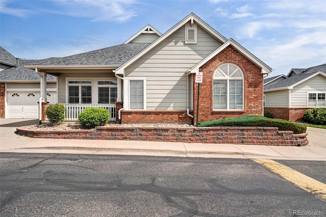 view of front of home with brick siding, an attached garage, concrete driveway, and roof with shingles