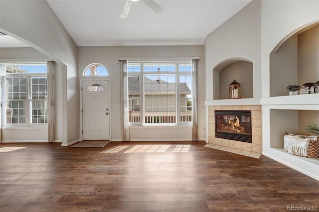 foyer entrance with plenty of natural light, wood finished floors, a ceiling fan, a tile fireplace, and lofted ceiling